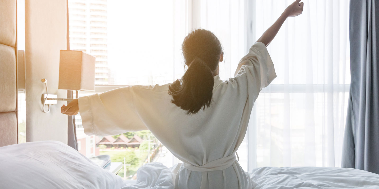 Person stretching in a bathrobe in a hotel room.