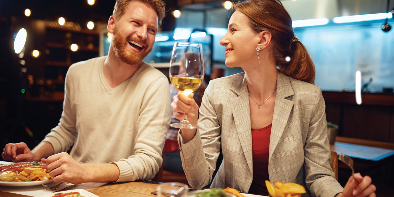 A happy couple having dinner with a glass of wine.