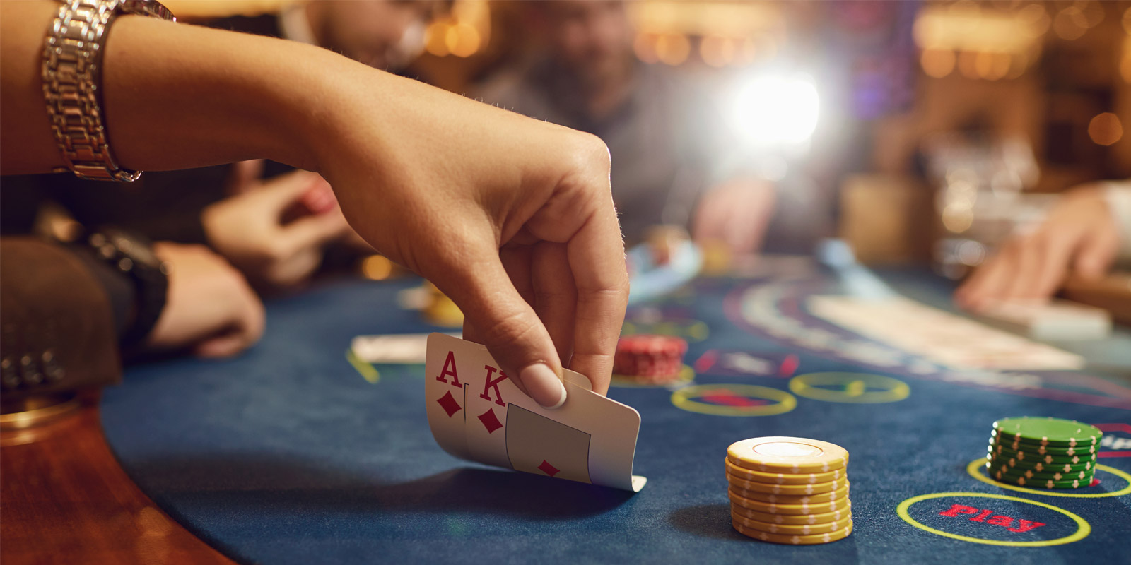 A hand lifting a pair of cards on a green felt table